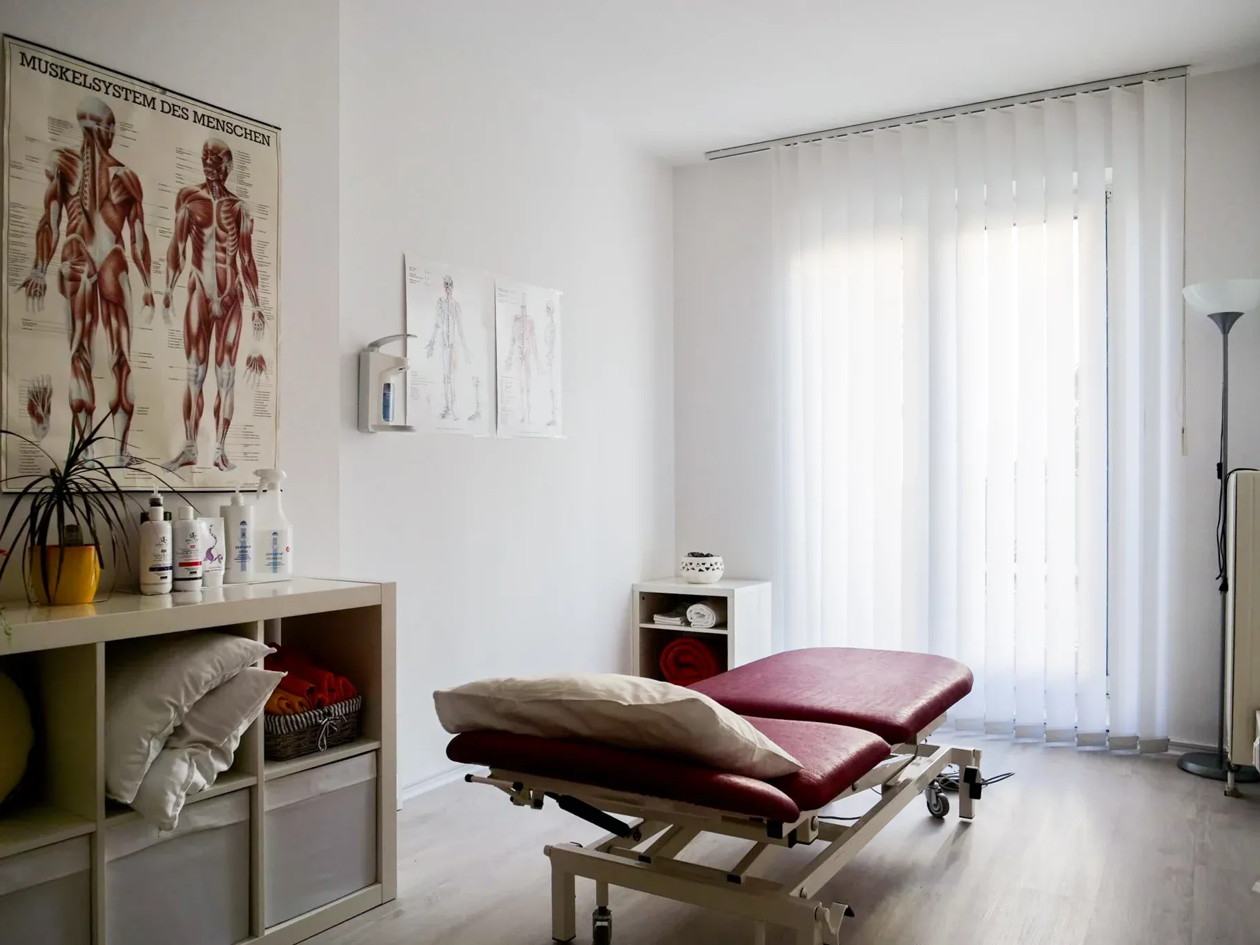 Behandlungsraum mit Therapieliege und Anatomie-Postern